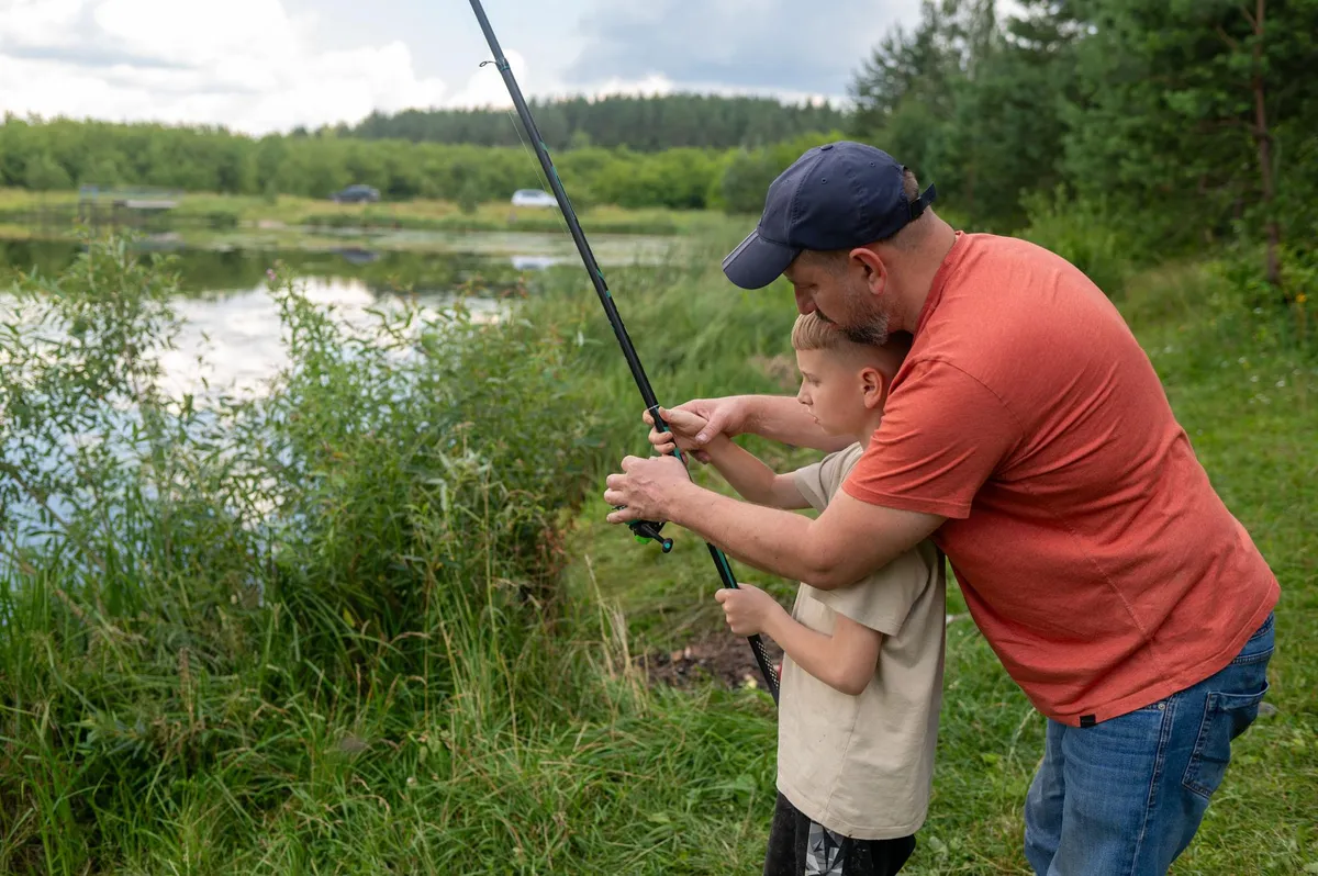 Father teaching son to fish at a pond